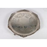 George V silver salver with gadroon edge and engraved scroll decoration, raised on four scroll