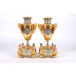Pair of French gilt metal and enamel clock garniture supporting vases of urn shape with mask