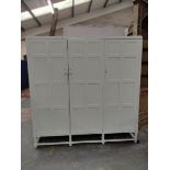 Painted oak triple wardrobe by Heals, the three multi panel doors enclosing drawers, trays and