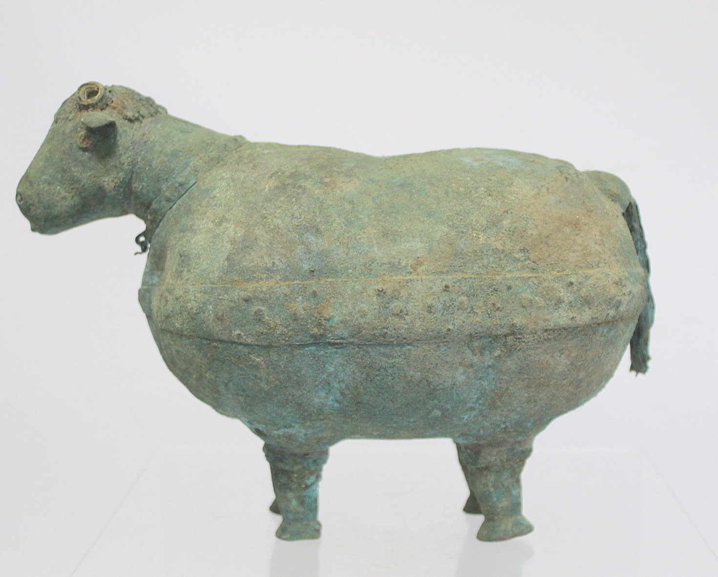 Archaistic naive hollow bronze figure of a ram, the rotund body with rivet effect band and collar