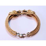 Chinese gold bracelet in two halves, modelled as dragons grasping a ring, Chinese character and