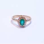 Diamond and emerald oval cluster ring, the emerald approximately 5mm x 4mm, and small diamond