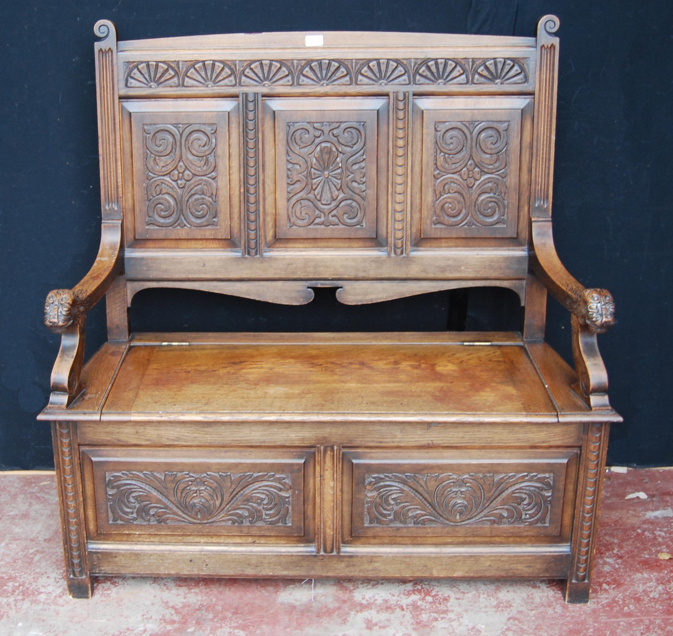 Oak hall settle with scroll panels, hinged seat and animal mask terminals, 124cm high, 122cm wide