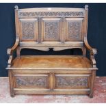 Oak hall settle with scroll panels, hinged seat and animal mask terminals, 124cm high, 122cm wide