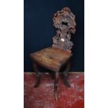 Black Forest carved oak hall chair, the naturalistic back rest applied with flowerheads and