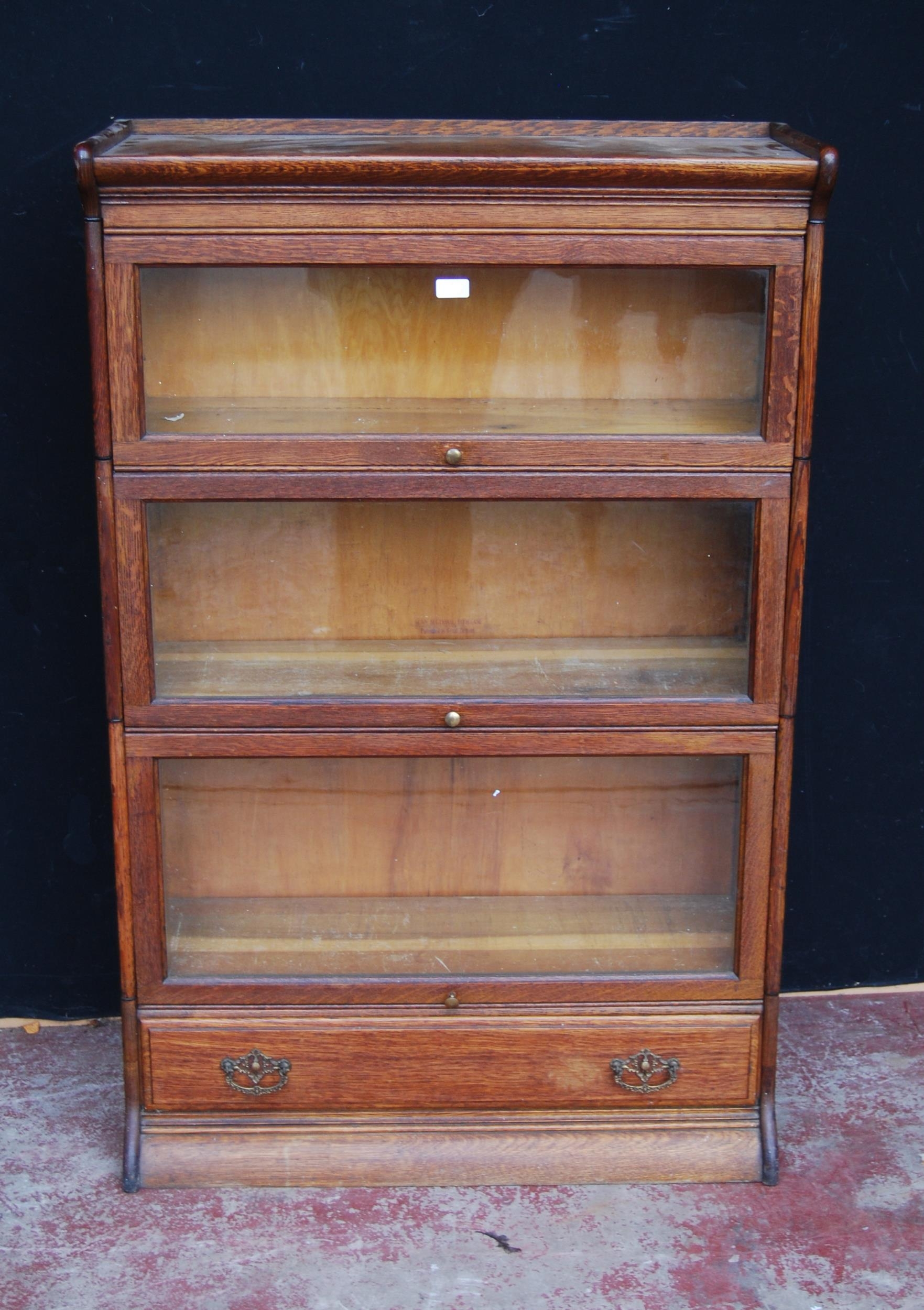 Oak sectional bookcase by Gunn Furniture Company, with three glazed sections above a long drawer,