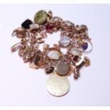 9ct gold charm bracelet with multiple charms and gems dependant to include a medal, ring, fob,