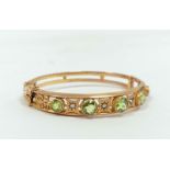 Victorian gold hinged bangle with five graduated circular peridots separated by eight cut