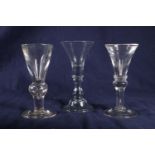 Two 18th Century deceptive glasses with restricted conical bowls and baluster knops on folding feet,
