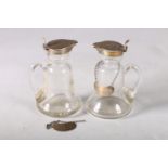 Pair of glass whisky noggins, having silver covers, engraved whisky labels, on star cut bases