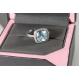 18ct white gold cocktail ring with square cut light blue stone encircled by diamond chips and also