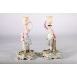 Pair of 19th Century Meissen candlesticks in the form of a man and woman supporting baskets to their