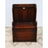 Oak hall seat in the form of a settle with carved lunettes to the frieze above a panelled back and