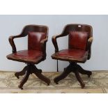 Pair of early 20th century oak revolving captain's desk chairs upholstered in later Rexine, metal