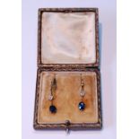 Pair of drop earrings, each with oval sapphire dependant from a diamond collet on knife edge.