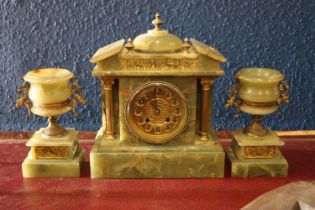 A green onyx clock garniture with brass dial and frieze with a Greek scene matching that of the