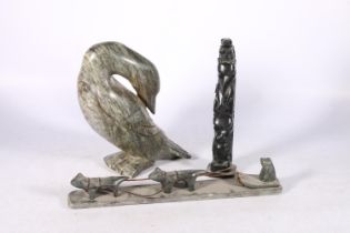 Three Canadian or Innuit soapstone carvings to include a hunter in sledge with two huskies, signed