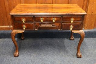 A 20th century walnut kneehole desk with five frieze drawers, brass handles, raised on shell