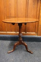 A Georgian mahogany oval occasional table, raised on turned column with three snake legs terminating