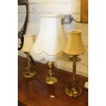 Three brass table lamps with shades.