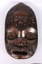 Large African carved dark indigenous wood mask in the form of a face, with further face flanked by