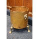 Large copper and brass coal bin with lion mask handles raised on paw feet, 45cm tall.