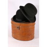 Two black bowler hats and a tin hat box.