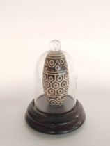 Tibetan inlaid Dzi Bead with all over geometric decoration, 9cm long, enclosed in a glass dome case.