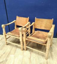 Pair of 20th century Indian easy chairs of teak construction with stretched leather back and arm