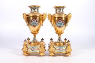 Pair of French gilt metal and enamel clock garniture supporting vases of urn shape with mask