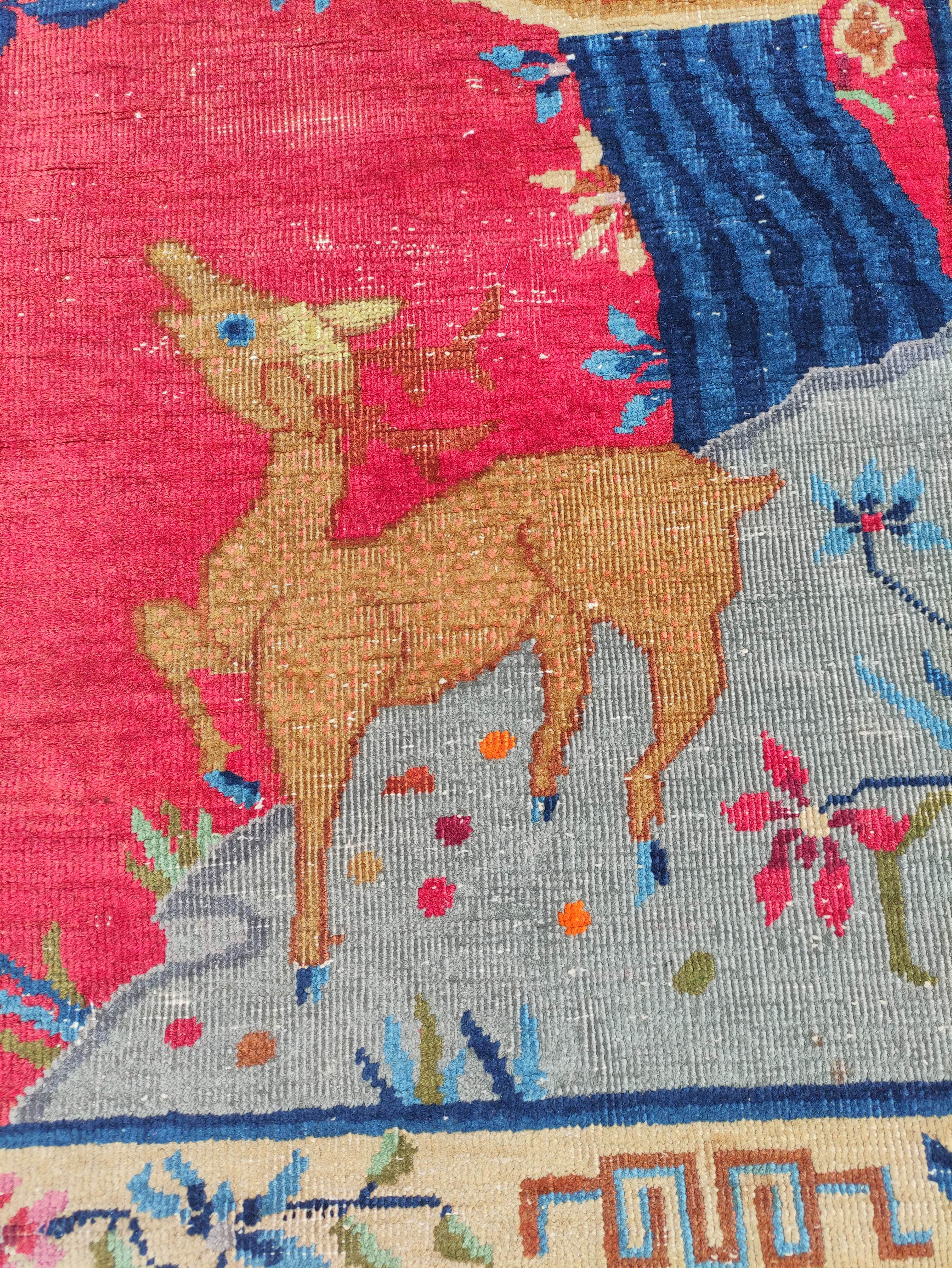 Chinese red ground rug, a deer in the corner below a blossom tree with birds, decorative cream guard - Image 3 of 4