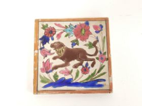 Antique Persian pottery tile decorated with polychrome subject of a lion amongst foliage &