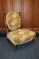 Victorian walnut framed nursing chair, upholstered in green floral patterned needlework covering,
