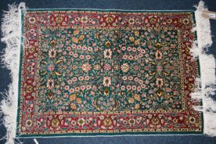 Indian silk rug, the green field decorated with millefiori design, red borders, fringed ends, 93cm x