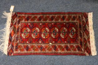 Turkoman mat sized rug, the red field with six guls, kelim style brocade ends, fringed, 100cm x