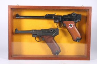 Wall display containing two replica Luger pistols, frame size 24.5cm x 37cm.