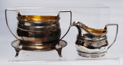 Silver milk jug and sugar basin of early 19th century ovoid shape, and a teapot stand, Glasgow 1905,