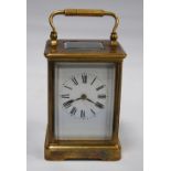 Brass four glass carriage clock with viewing window to the top displaying the movement, the white