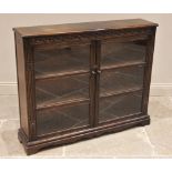 An oak Priory style glazed bookcase, mid 20th century, the rectangular moulded top above a pair of