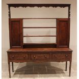 A George III oak and mahogany crossbanded dresser, the open plate rack with a moulded cornice and