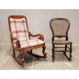 A Victorian mahogany framed rocking chair, the scroll arms enclosing a drop in upholstered seat,