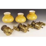 Three brass oil lamp wall sconces, late 19th century, the Duplex burner reservoirs seated within