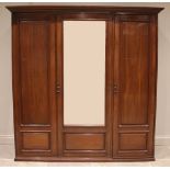 A large Edwardian walnut gentleman's triple wardrobe, the central bevelled mirror door flanked by