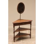 An oak corner shaving stand, circa 1920, the adjustable oval mirror above three triangular tiers,