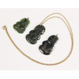 Three New Zealand jade Tiki pendants, one with attached yellow metal chain, largest 4cm, smallest