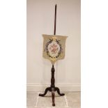 A Victorian mahogany pole screen, the shield shaped floral tapestry screen upon a slender pole and