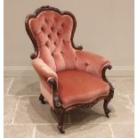 A Victorian carved walnut and rose pink velour salon chair, the shaped button back framed by a