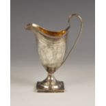 A George III silver cream jug, London 1796, of helmet form on square base with loop handle, chased