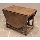 An 18th century style honey oak drop leaf dining table, the oval top upon barley twist and block