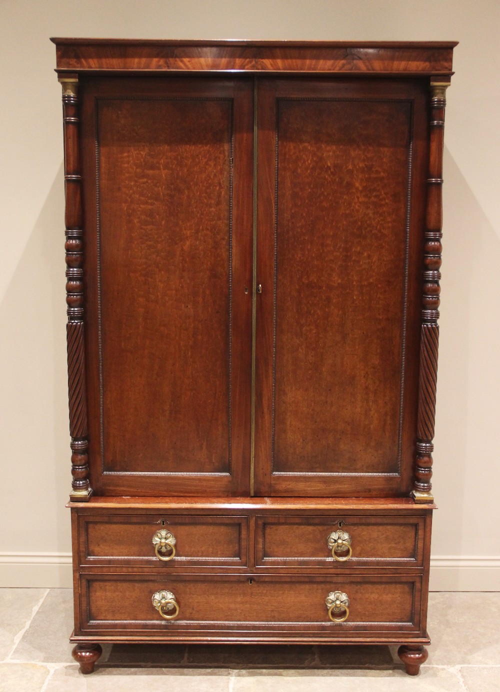 A William IV plum pudding mahogany wardrobe, the moulded cornice and plain frieze over a pair of